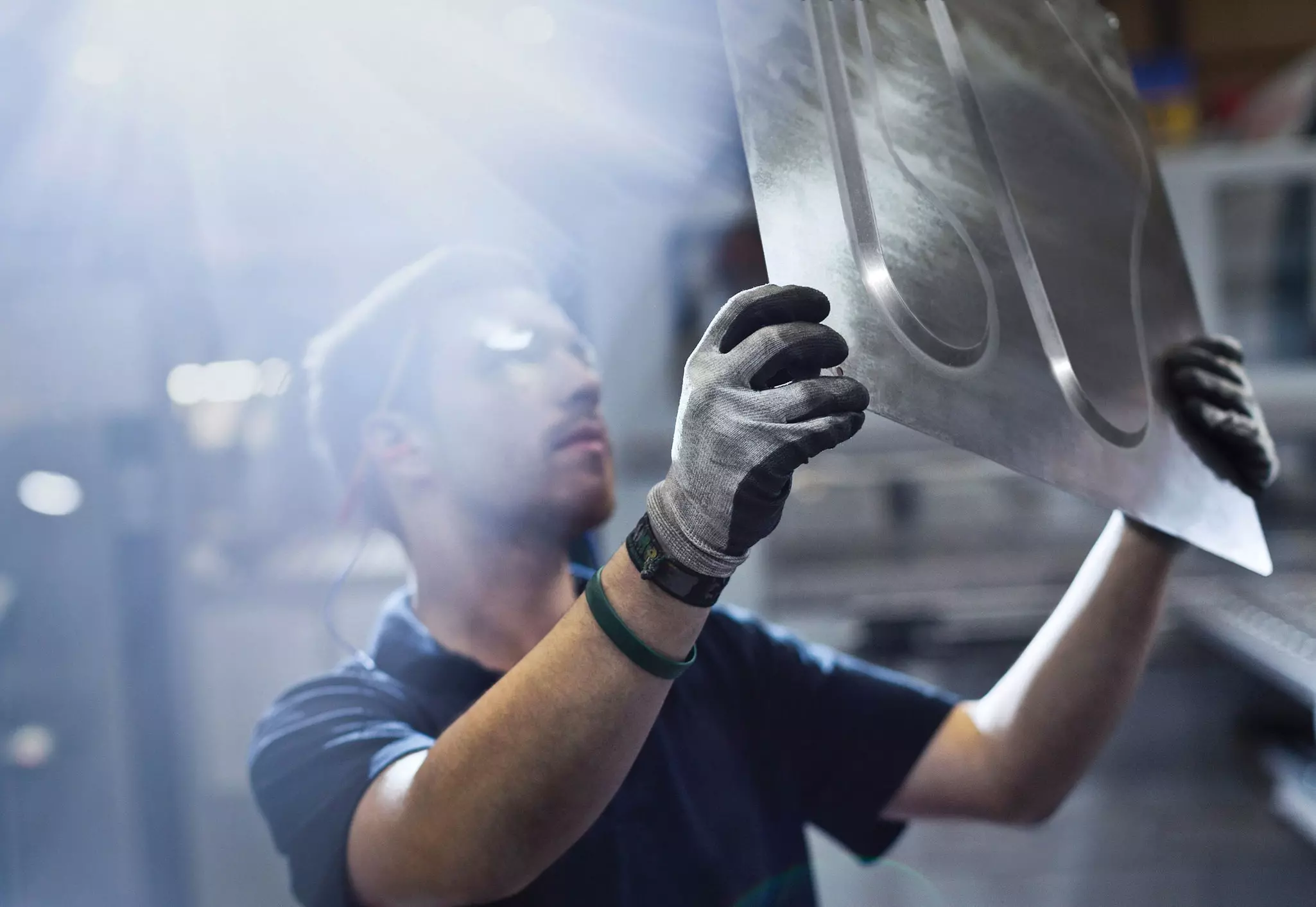 man holding up a formed piece of sheet metal